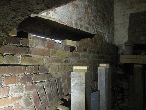 Над уже выложенной аркой оставшееся пространство до фасадной стены заложили кирпичами, постепенно убирая из стены шатающиеся кирпичи.