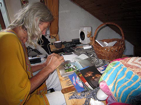 Istvan Sky in einer gelben Kurta an seinem Arbeitstisch im Obergeschoss des Hauses beim Signieren von Album-CDs.