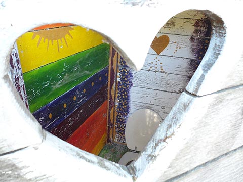 Herzförmiges Toilettenfenster mit fröhlich gestalteten Innenwänden. Haus von István Napfényszentély in Szentbékkállá, Ungarn.