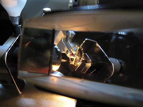 Jean Widmer-Steiner zum Auswuchten einer Schraubenunruh Typ 2. Sehr nahe Ansicht der Unruh durch das Prisma mit Linse.